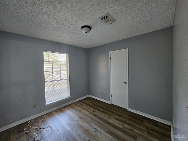 unfurnished room with dark hardwood / wood-style floors and a textured ceiling