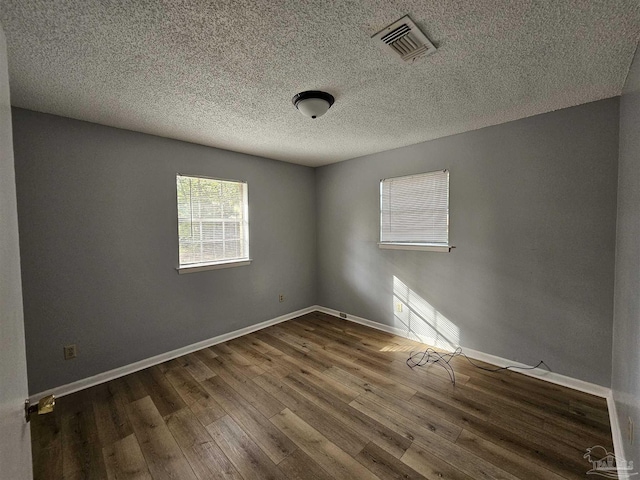 spare room with a textured ceiling and dark hardwood / wood-style flooring