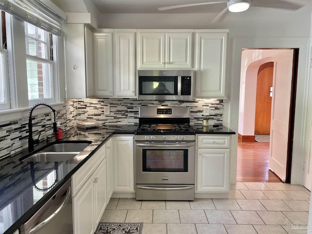 kitchen featuring white cabinets, sink, appliances with stainless steel finishes, tasteful backsplash, and light tile patterned flooring