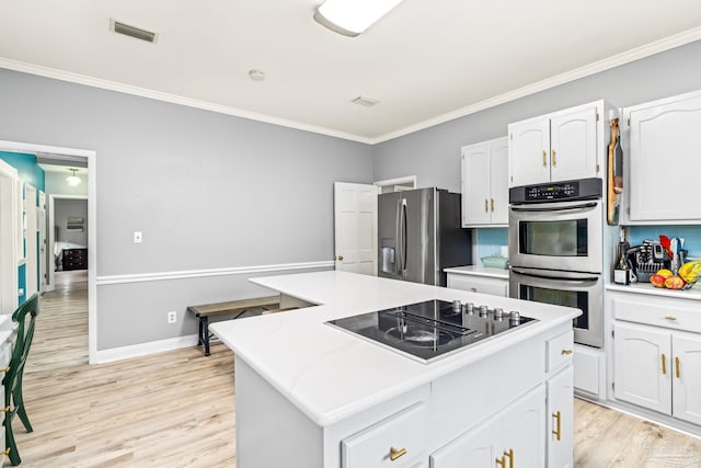 kitchen with crown molding, visible vents, stainless steel appliances, and a kitchen island