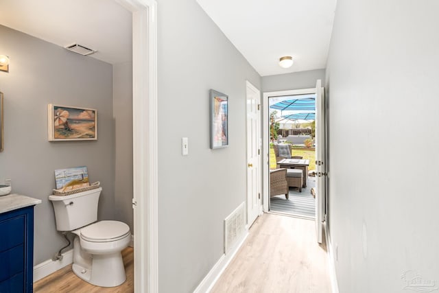 corridor with baseboards, visible vents, and light wood-type flooring