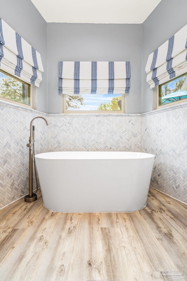 bathroom with wainscoting, wood finished floors, and tile walls