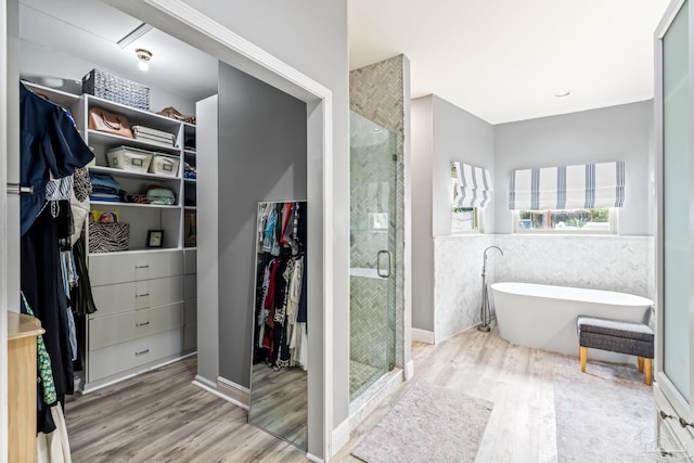 full bath with tile walls, wood finished floors, a walk in closet, and a shower stall