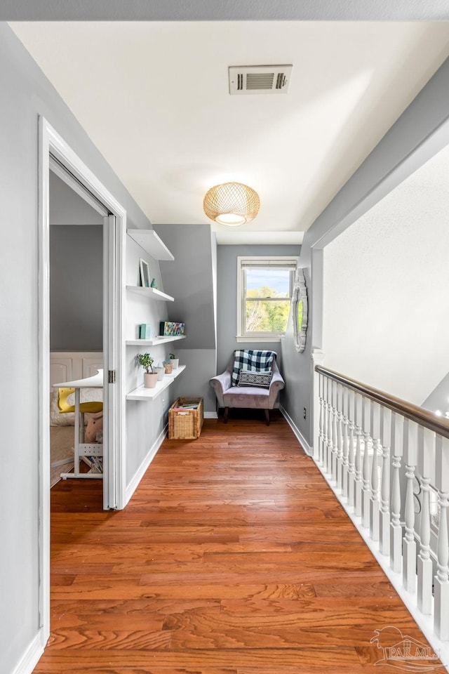 corridor with baseboards, visible vents, built in features, and wood finished floors