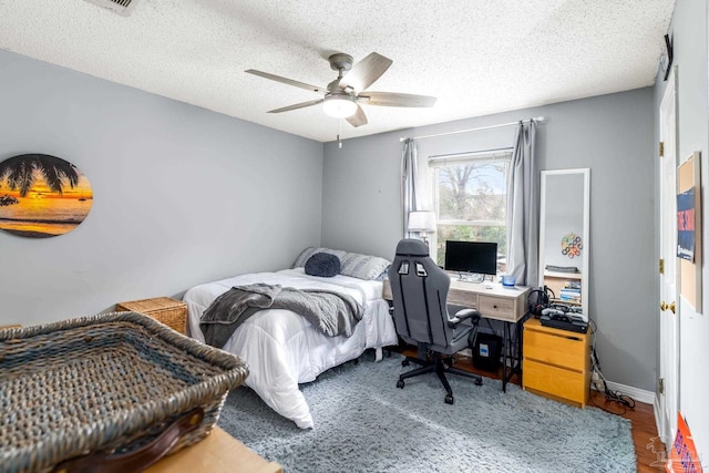 bedroom featuring baseboards, a ceiling fan, wood finished floors, and a textured ceiling