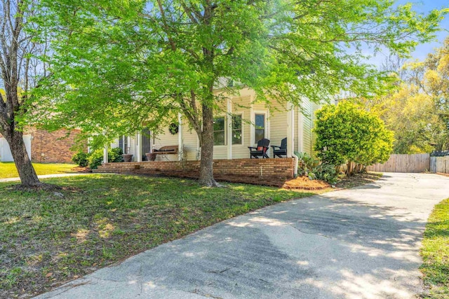 exterior space featuring a lawn, fence, and concrete driveway