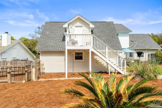 back of property featuring fence, stairway, and roof with shingles