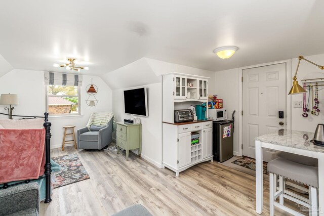 bedroom with refrigerator, baseboards, light wood-style floors, and vaulted ceiling