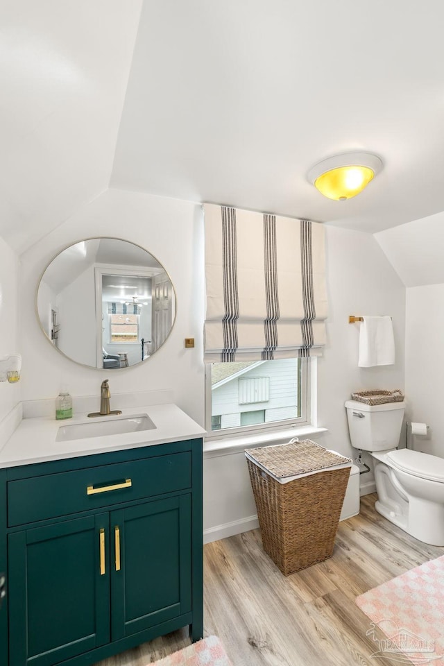 bathroom featuring toilet, vanity, wood finished floors, lofted ceiling, and baseboards