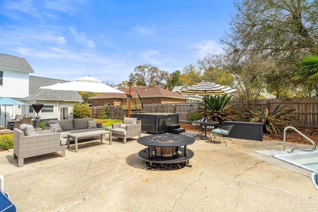 view of patio featuring a hot tub, a fenced backyard, and an outdoor living space with a fire pit
