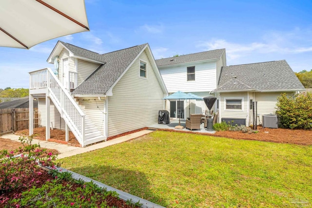 rear view of house featuring stairway, fence, roof with shingles, a patio, and a lawn
