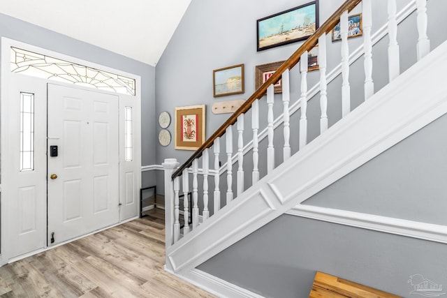 entryway featuring stairs, wood finished floors, and vaulted ceiling