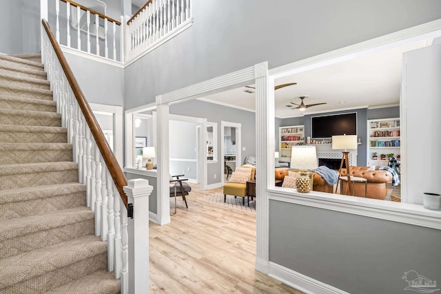 stairway featuring baseboards, ceiling fan, wood finished floors, and crown molding