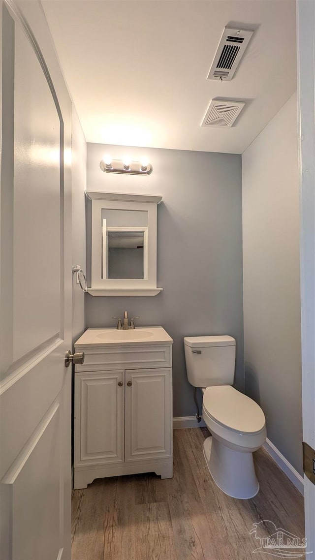 bathroom featuring wood-type flooring, vanity, and toilet