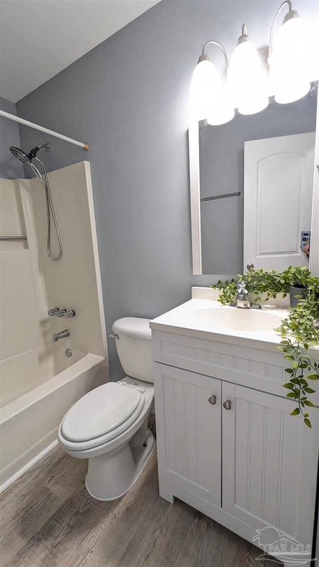 full bathroom featuring washtub / shower combination, hardwood / wood-style floors, vanity, and toilet