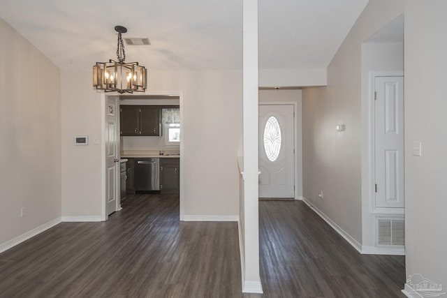 foyer entrance with a chandelier, dark wood-style flooring, visible vents, and baseboards