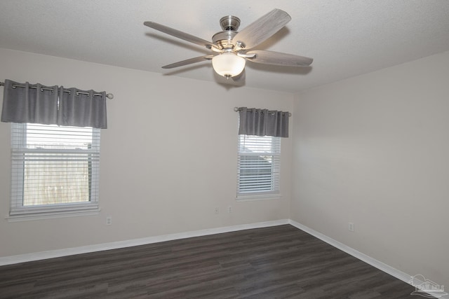 spare room featuring a textured ceiling, ceiling fan, dark wood-style flooring, and baseboards