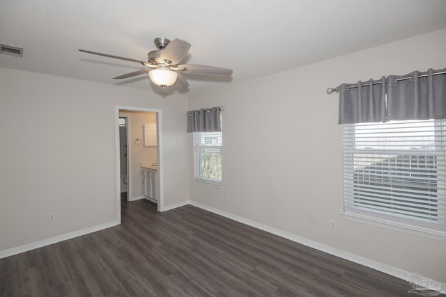 spare room with baseboards, visible vents, ceiling fan, dark wood-type flooring, and a textured ceiling