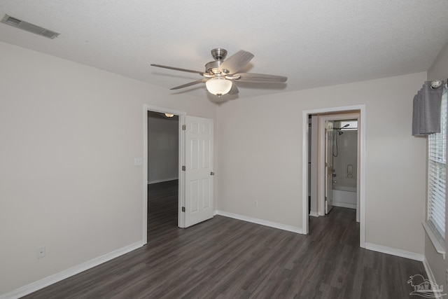 unfurnished bedroom featuring baseboards, visible vents, dark wood finished floors, and a textured ceiling