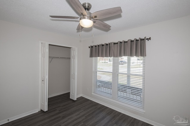 unfurnished bedroom with a textured ceiling, dark wood-type flooring, a ceiling fan, baseboards, and a closet