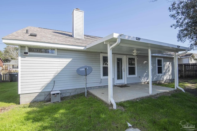 back of property with a yard, a chimney, a patio area, and fence