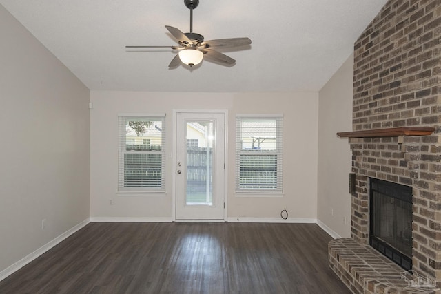 unfurnished living room featuring a brick fireplace, dark wood-style floors, vaulted ceiling, and a wealth of natural light