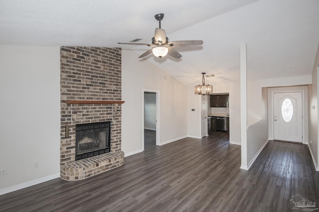 unfurnished living room with baseboards, lofted ceiling, dark wood-style floors, a brick fireplace, and ceiling fan with notable chandelier