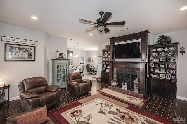 living room featuring a brick fireplace and ceiling fan with notable chandelier