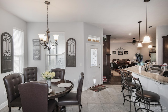 tiled dining space with sink and ceiling fan with notable chandelier