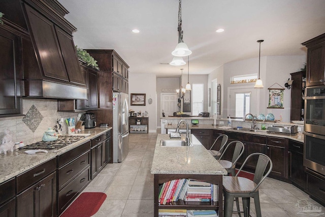 kitchen with premium range hood, appliances with stainless steel finishes, decorative light fixtures, and sink