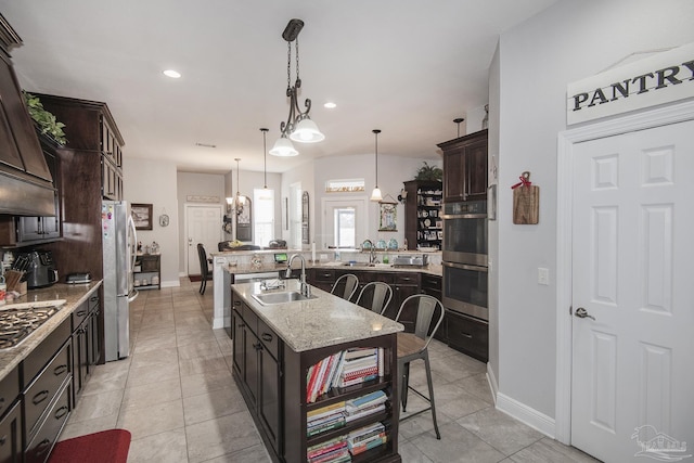 kitchen featuring sink, a kitchen breakfast bar, dark brown cabinetry, stainless steel appliances, and a center island with sink