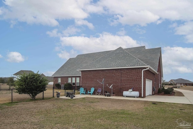 rear view of property with a garage, a yard, and a patio area