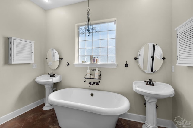 bathroom featuring tile patterned flooring, a tub to relax in, sink, and a chandelier