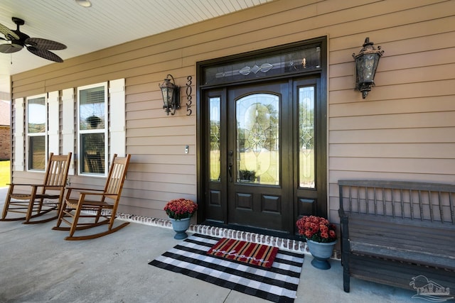 view of exterior entry with ceiling fan and a porch