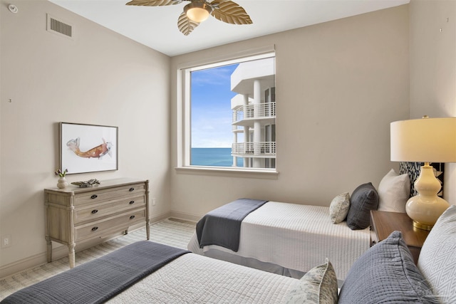 bedroom with ceiling fan and a water view