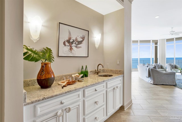 bathroom with a water view, ceiling fan, expansive windows, and vanity