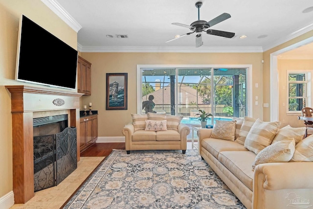 living room featuring ornamental molding, a tile fireplace, ceiling fan, and hardwood / wood-style floors