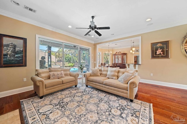 living room with light wood-type flooring, ceiling fan with notable chandelier, and ornamental molding