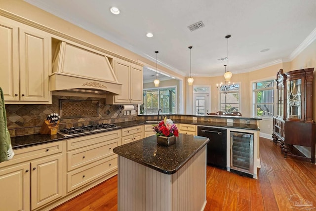 kitchen featuring stainless steel gas cooktop, a center island, beverage cooler, hardwood / wood-style flooring, and custom range hood