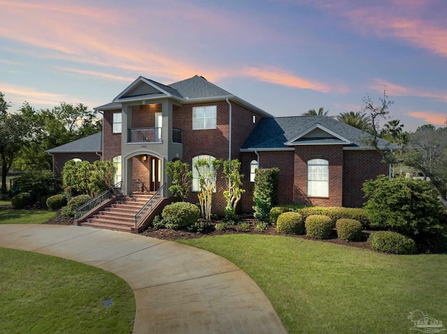 view of front of property featuring a balcony and a lawn