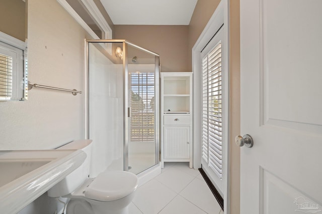 bathroom with a shower with door, tile patterned flooring, and toilet