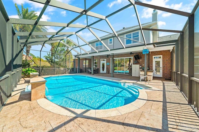 view of swimming pool featuring a patio, glass enclosure, and ceiling fan