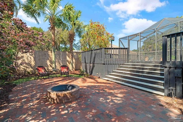 view of patio / terrace featuring an outdoor fire pit and glass enclosure