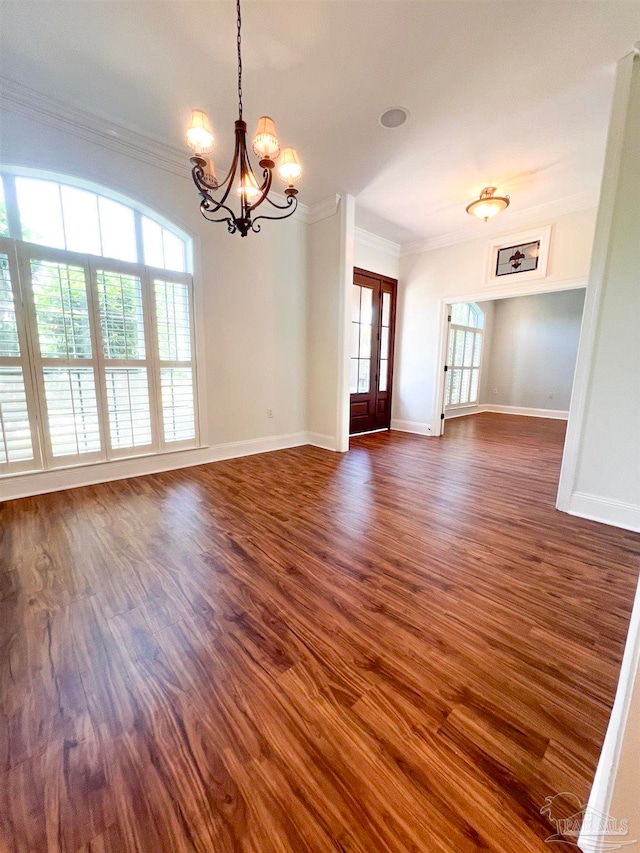 empty room featuring ornamental molding, dark hardwood / wood-style flooring, and an inviting chandelier