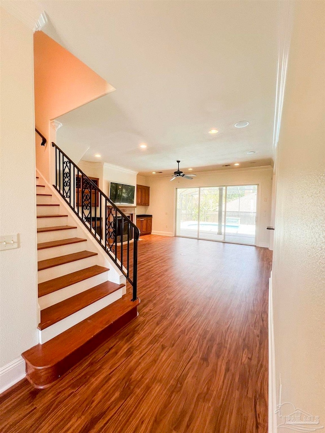 stairway featuring ceiling fan, hardwood / wood-style flooring, and ornamental molding