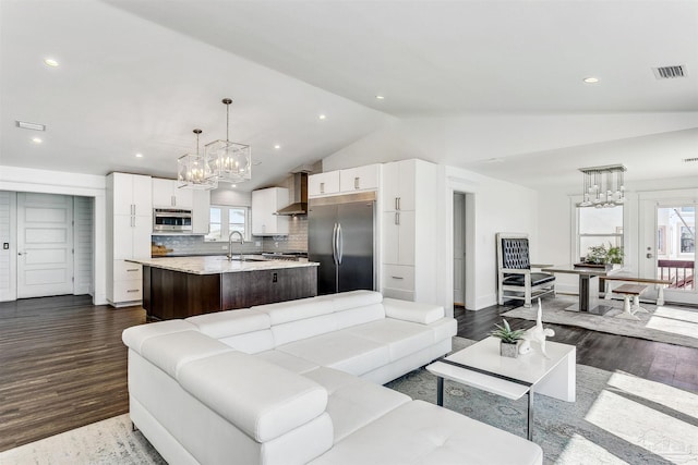 living room with an inviting chandelier, high vaulted ceiling, sink, and dark hardwood / wood-style flooring