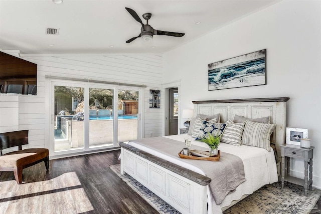 bedroom with wooden walls, access to outside, vaulted ceiling, and dark wood-type flooring