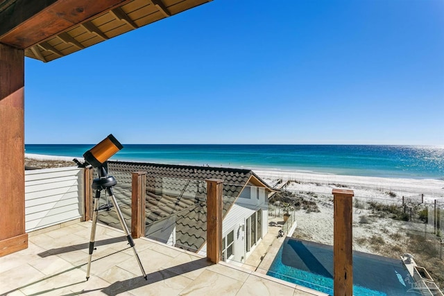 balcony with a patio, a water view, and a beach view