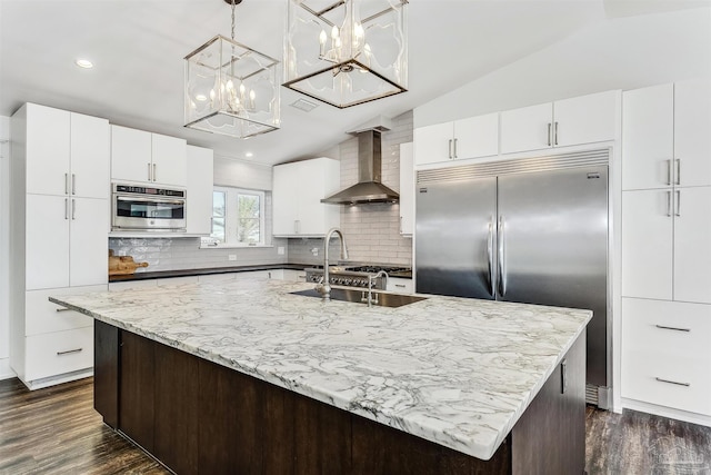 kitchen featuring lofted ceiling, wall chimney range hood, dark hardwood / wood-style floors, appliances with stainless steel finishes, and decorative backsplash