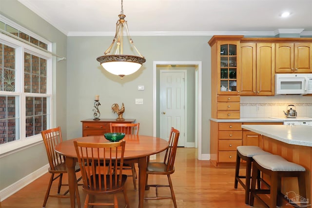 dining space featuring ornamental molding and light hardwood / wood-style floors